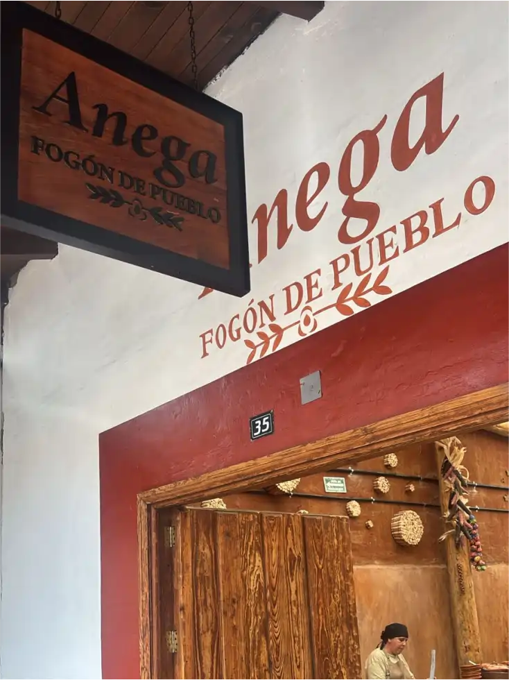 Entrada de Anega Fogón de Pueblo, con su letrero de madera y mural en Galeana 35